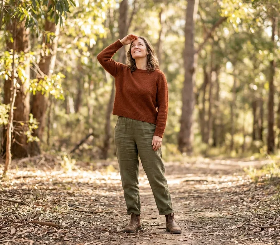 Woman standing on a eucalypt bush track in the Illawarra, looking up through the canopy